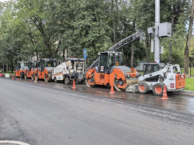 Heavy machinery lined up for road construction in a city.